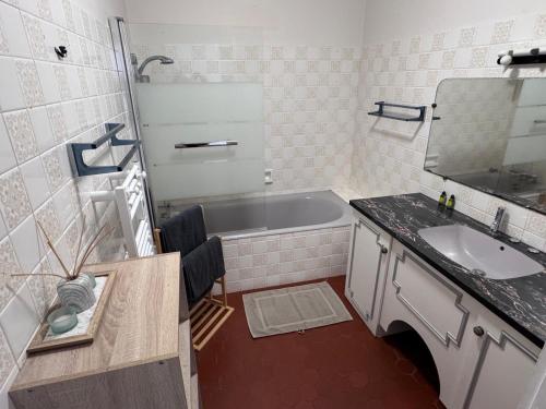 une salle de bain avec une baignoire, un lavabo et un miroir dans l'établissement Le Mousseau Proche de Chambord, à Mer