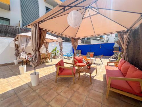 a large umbrella on a patio with chairs and tables at The Beach House Paradise by Hello Homes Sitges in Sitges