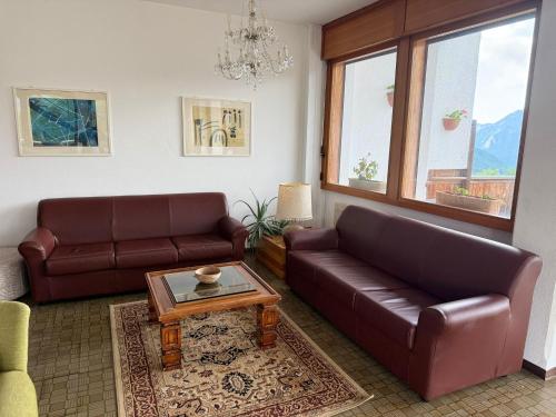 a living room with two leather couches and a coffee table at HG Hotel La Caminatha in Val di Zoldo