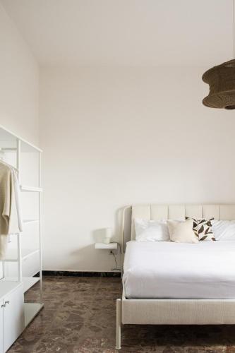 a white bedroom with a bed and a mirror at Dimora Oro - Slow Life in Sardinia in Assemini
