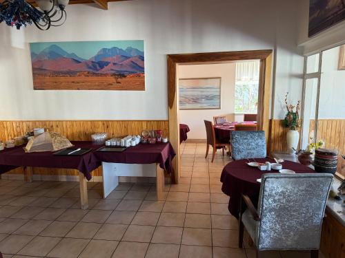 a room with two tables and a dining room with mountains at Hotel Pension Steiner in Windhoek