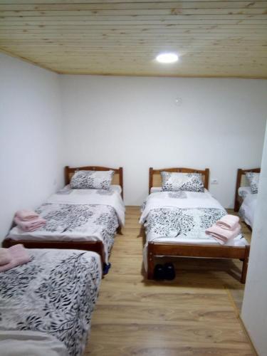 three beds in a room with wooden ceilings at Bujtina Sherifaj in Valbonë