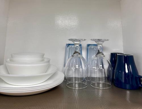 three wine glasses and plates and bowls on a table at South Breeze Stay Near Nuvali, Enchanted kingdom, Tagaytay in Silang