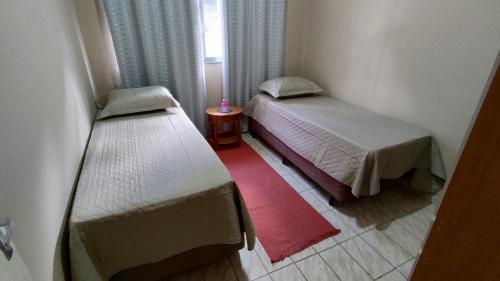 a small room with two beds and a window at Aptos em Duas Barras - RJ in Duas Barras