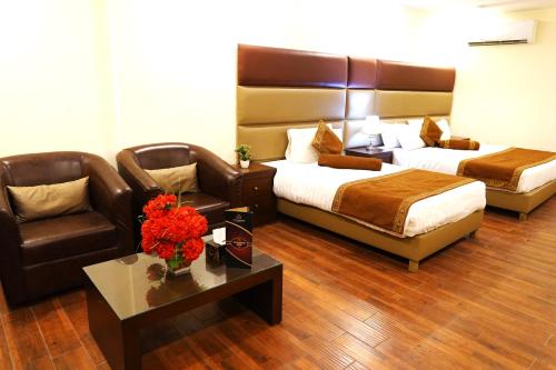 a hotel room with two beds and a couch and a table at Grand Millennium Hotel in Lahore