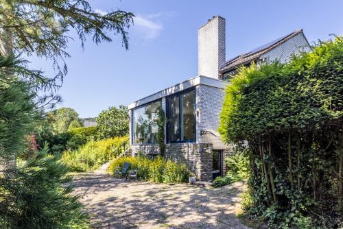 a brick house with glass windows and plants at B&B Nouveauté in Vaals