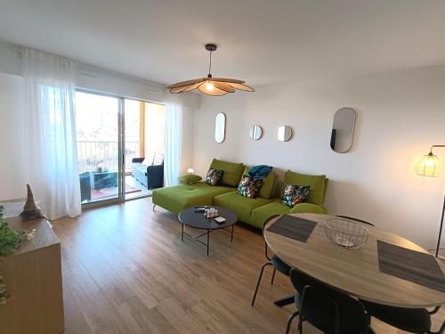 un salon avec un canapé vert et une table dans l'établissement le contemporain, à Bastia