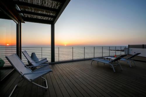 two chairs and a table on a deck with the sunset at Hotel Punta Tipa in Trapani