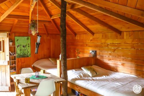 une chambre avec deux lits dans une cabane en bois dans l'établissement Le Mas des Pins, à Beynes