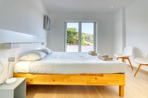 een witte slaapkamer met een houten bed en een raam bij Nice Home Costa Adeje in Adeje
