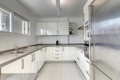 een keuken met witte kasten en een roestvrijstalen koelkast bij Nice Home Costa Adeje in Adeje