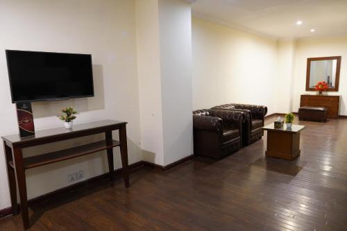 a living room with a couch and a flat screen tv at Grand Millennium Hotel in Lahore