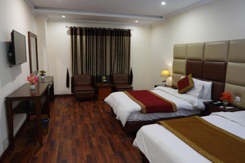 a hotel room with two beds and a desk at Grand Millennium Hotel in Lahore