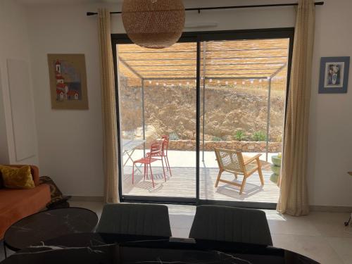 un salon avec une grande fenêtre avec des chaises et un patio dans l'établissement Magnifique appartement T2, à Cuttoli-Corticchiato