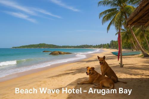 two dogs sitting on a beach near the ocean at Beach Wave Hotel in Arugam Bay