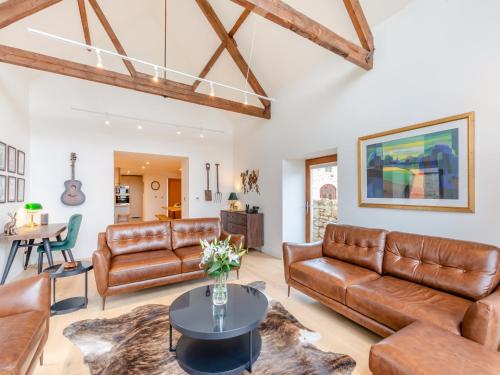 a living room with leather furniture and a table at Haybale Barn in Chatton
