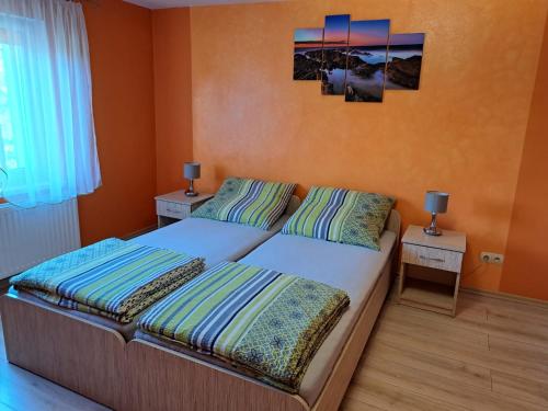 a bedroom with two beds with orange walls and two lamps at Noclegi u Agnieszki in Jarnołtówek