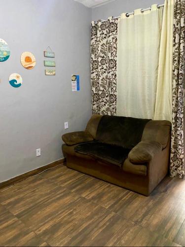 a brown couch in a room with a curtain at BLUE HOUSE CONEXÃO ILHA GRANDE in Abraão