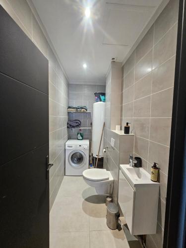 a bathroom with a toilet sink and a washing machine at studio 2 personnes toutes équipées in Malataverne