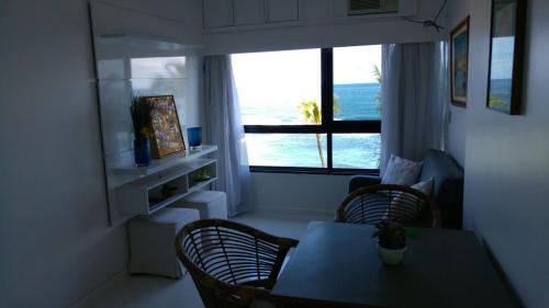 a living room with a table and chairs and a window at Apart Hotel de Ondina in Salvador