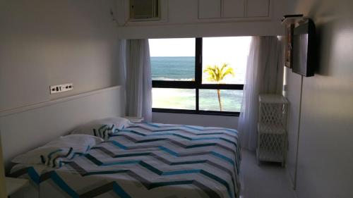 a bedroom with a bed and a view of the ocean at Apart Hotel de Ondina in Salvador