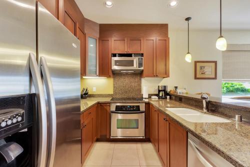a kitchen with wooden cabinets and a stainless steel refrigerator at Castle Hali'i Kai at Waikoloa in Waikoloa