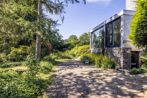 a garden with a brick building and trees at B&B Nouveauté in Vaals