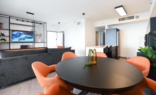 a living room with a black table and orange chairs at Yalarent C Kinneret Apartments With Private Jacuzzi in Migdal