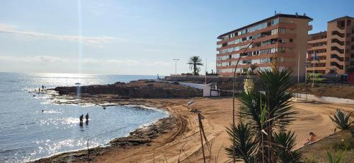 a beach with people in the water and a building at Relax & Sea Apartment - Cabo Cervera - Torrevieja in Torrevieja
