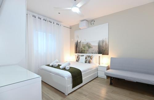 a white bedroom with a bed and a bench at Yalarent C Kinneret Apartments With Private Jacuzzi in Migdal