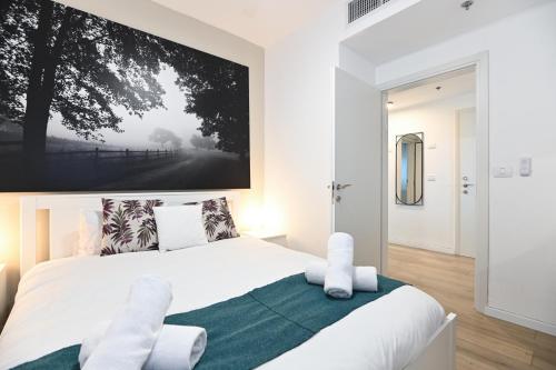 a bedroom with a white bed with a large picture on the wall at Yalarent C Kinneret Apartments With Private Jacuzzi in Migdal