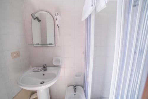 a white bathroom with a sink and a toilet at Hotel Isola Bella in Taormina