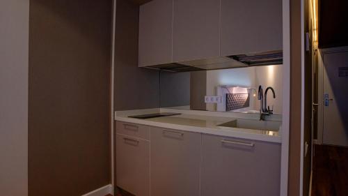 a kitchen with white cabinets and a sink at Alliance Palace Seaside in Batumi