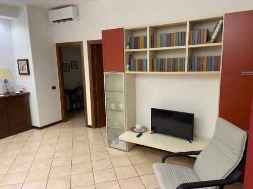 a living room with a tv and a chair and book shelves at Ca Nora in Sasso Marconi