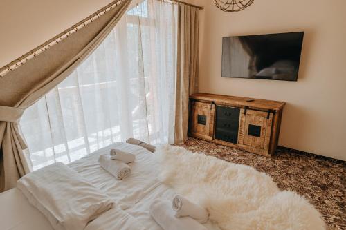 a bedroom with a white bed with a large window at Chalets CEDER 2 in Tatranská Lomnica