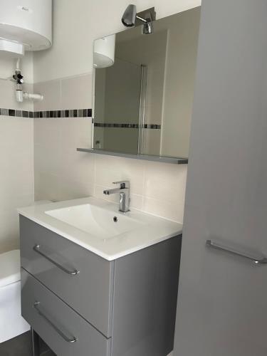 une salle de bain blanche avec un lavabo et un miroir dans l'établissement Studio élégant, central, pour 2 personnes, à Pornic