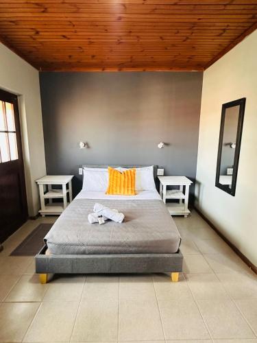 a bedroom with a bed with orange pillows and two tables at Aruwaa in East London