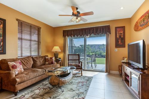a living room with a couch and a flat screen tv at Castle Hali'i Kai at Waikoloa in Waikoloa