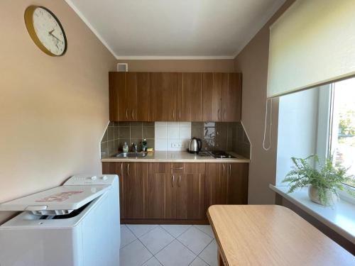 een keuken met houten kasten en een klok aan de muur bij Elena in Ventspils