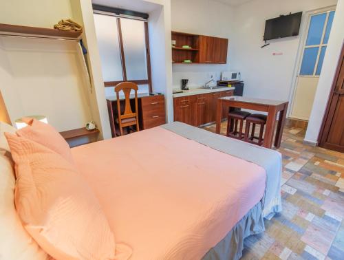 a bedroom with a large bed and a kitchen at Casa Mayahuel in Oaxaca City