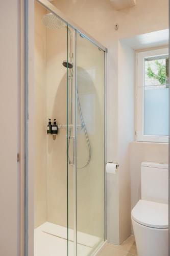 La salle de bains est pourvue d'une douche en verre et de toilettes. dans l'établissement Le patio - Une cours intérieur au coeur du vieux Dinan, à Dinan