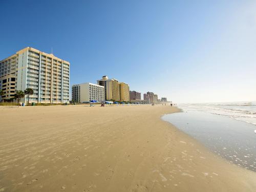 a beach with buildings in the background and the ocean at Holiday Sands at South Beach in Myrtle Beach