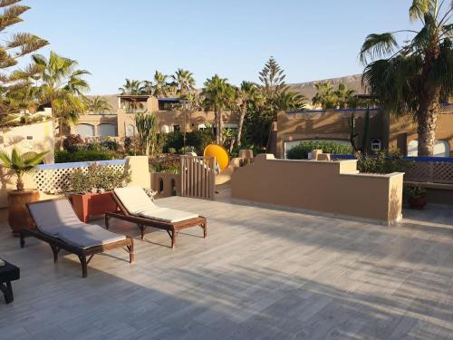 a patio with chairs and a fence and palm trees at Villa bord de mer, piscine, fibre internet, Sidi Boulfdail, Mirleft in Mirleft