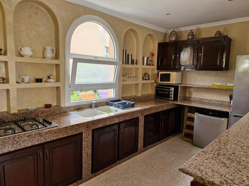 a large kitchen with a sink and a window at Villa bord de mer, piscine, fibre internet, Sidi Boulfdail, Mirleft in Mirleft
