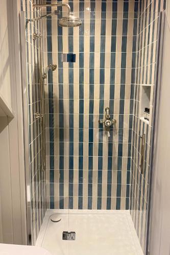 une salle de bain avec douche aux carreaux bleus et blancs dans l'établissement Stamping Cottage near Isles of Scilly Park and Ride, à Penzance