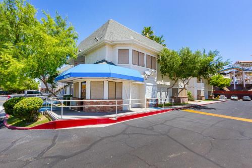 a white house with a blue awning on a street at Motel 6-Mesa, AZ - South in Mesa