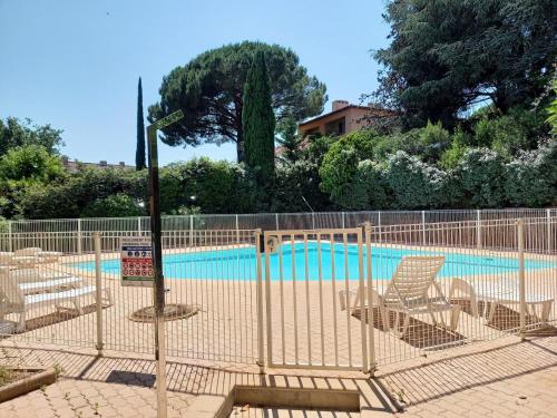 a fence with lounge chairs next to a swimming pool at Résidence Villa Antoinette - maeva Home - Appartement 3 pièces 4 personnes - Exclusive MAE-6573 in Grimaud
