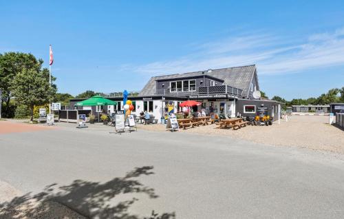 a building with tables and chairs in front of it at Holiday Home Stikkelsbærvej Tarm Iv in Hemmet