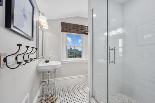 a white bathroom with a sink and a shower at 525 Route 28 Harwich Port Cape Cod - - The Mooring in Harwich Port