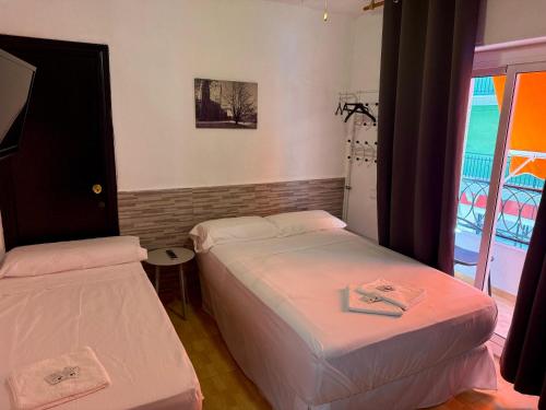 two beds in a small room with a window at PENSIÓN ROSA in Benidorm